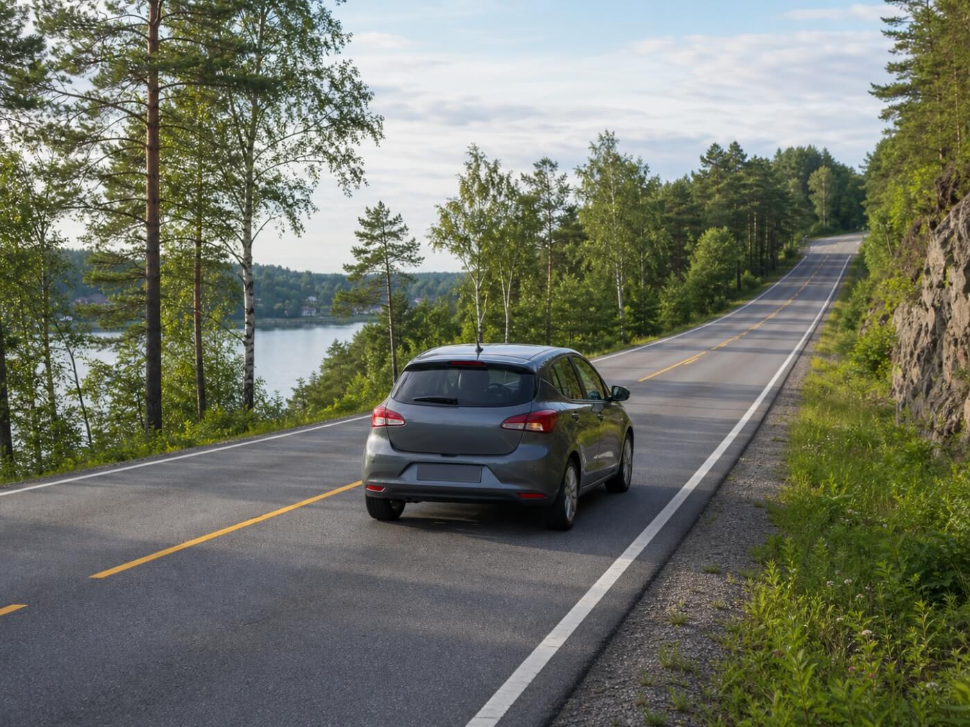 Voiture compacte sur une route arborée au bord de l’eau, à la sortie d’Oslo.